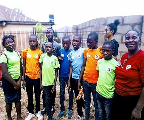 Children in brightly coloured T-shirts standing outdoors with adult volunteers