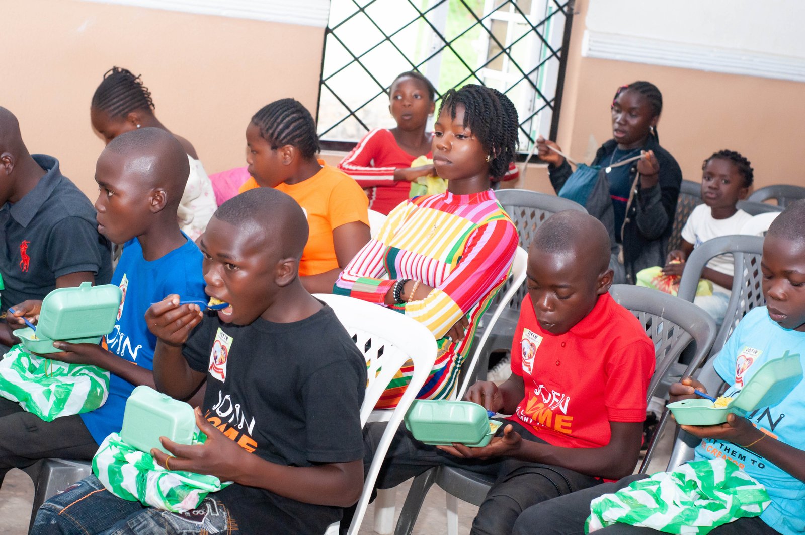 Children in JOFIN T-shirts sharing a meal together from food packs