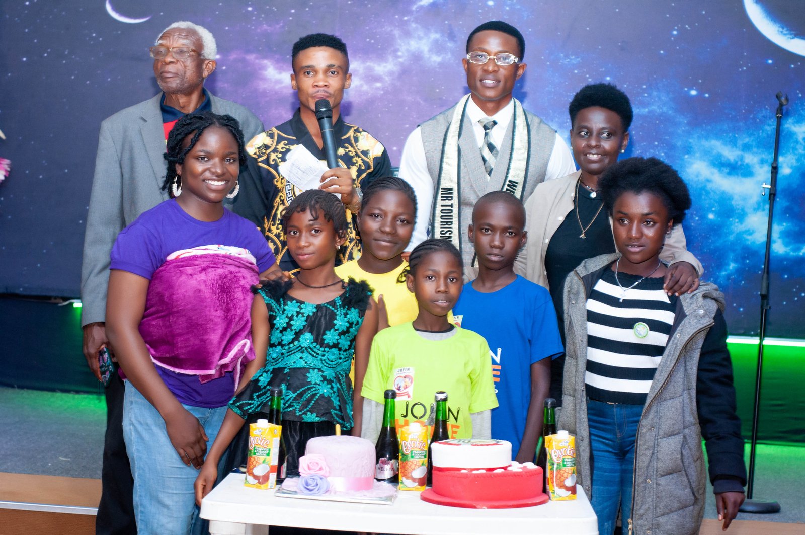 Adults and children standing together behind celebration cakes