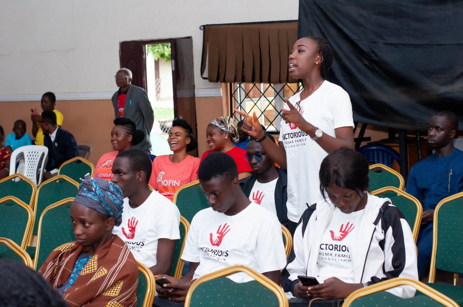 Young volunteers in matching T-shirts seated together at a JOFIN gathering