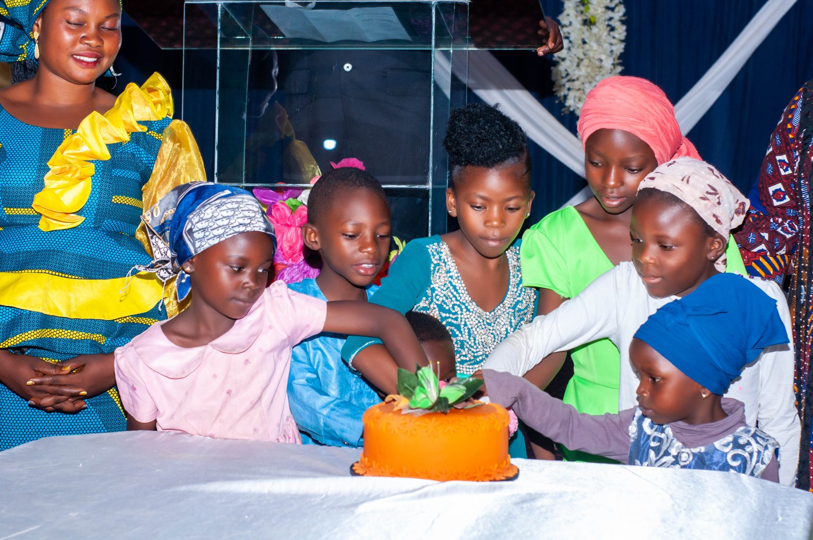 Girls from JOFIN Home cutting a celebration cake together with a caregiver