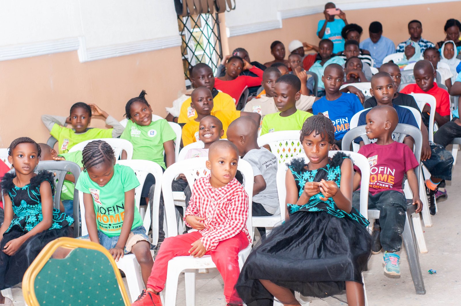 Children and adults seated together at a JOFIN community gathering